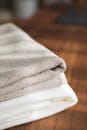 A close-up shot of neatly folded soft linen blankets on a wooden floor.